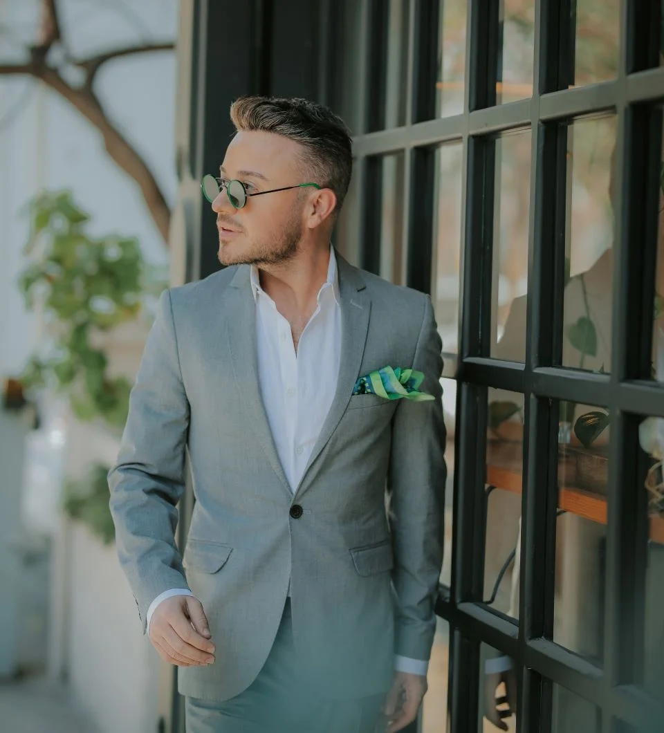 young-man-looking-away-while-standing-against-window